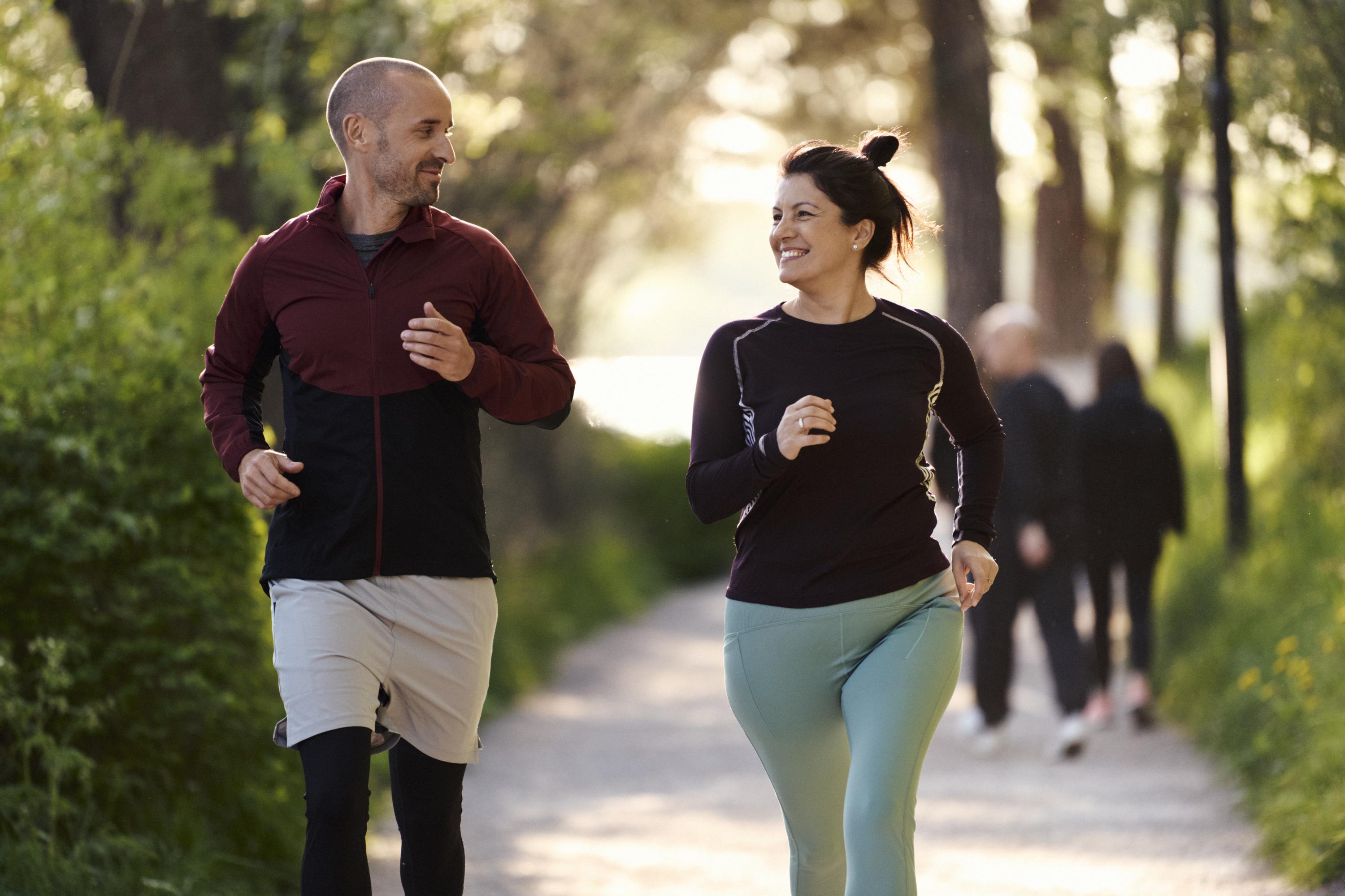 En man och en kvinna joggar på en grusväg